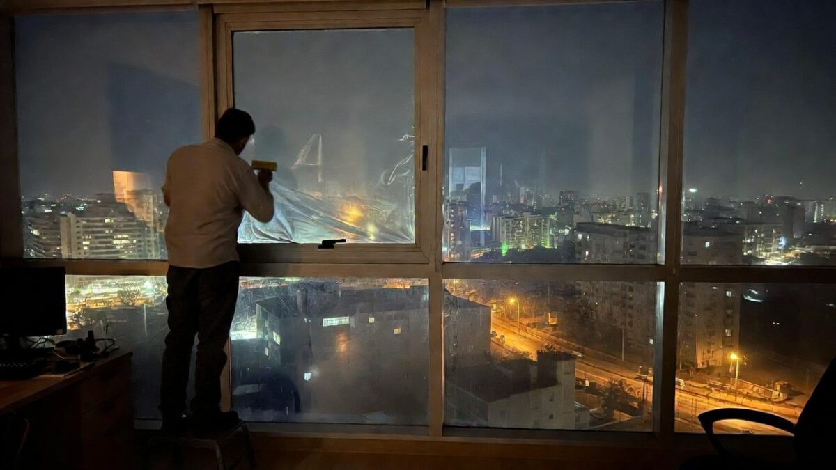person installing window film at night image